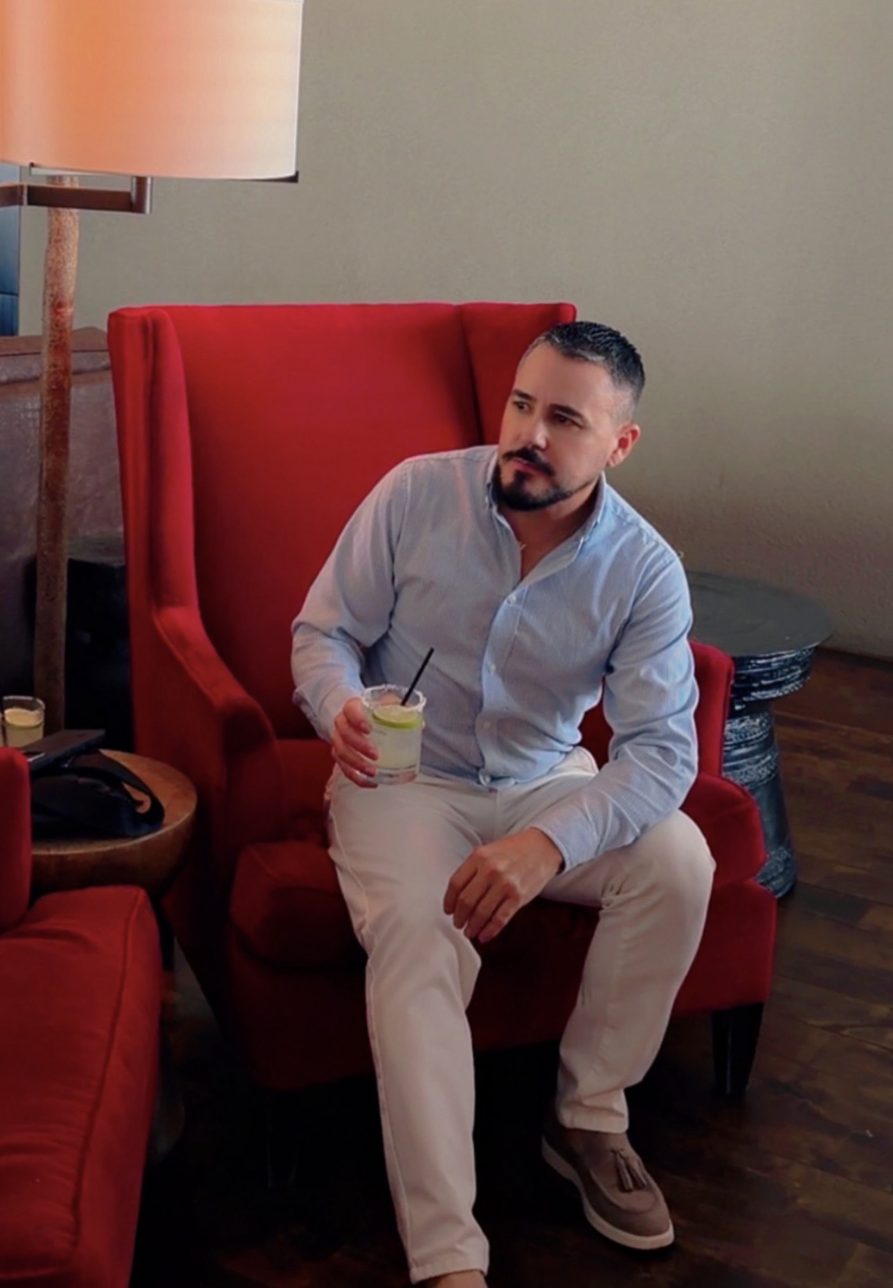 Alex, the stylist, seated in a red armchair